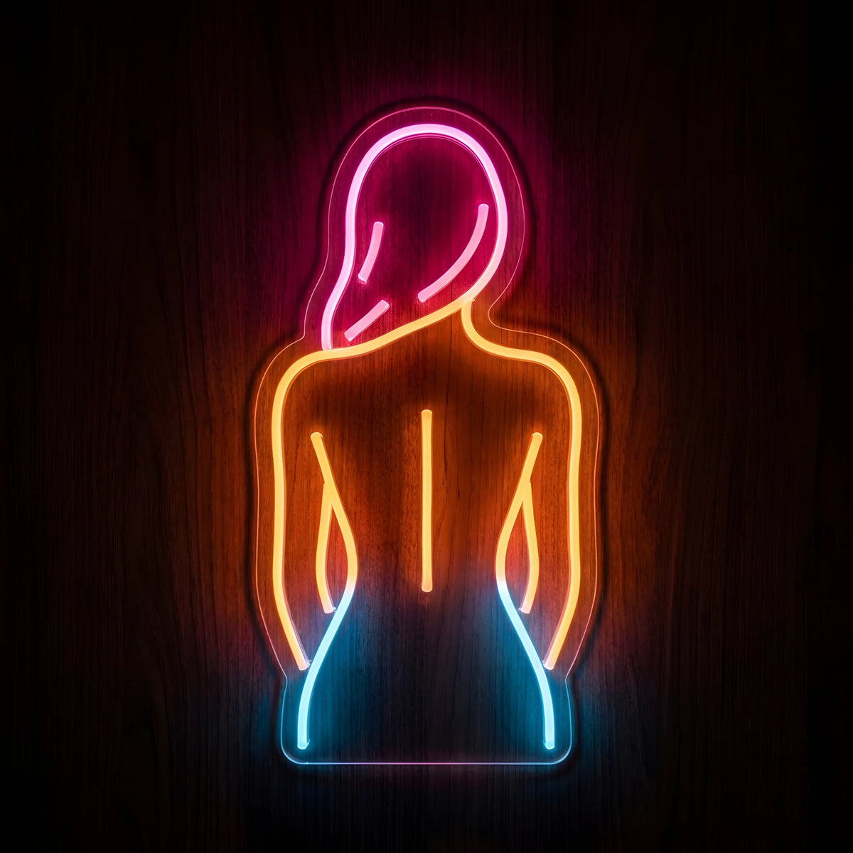 Back and Spine Therapy LED Neon Sign featuring a woman's back silhouette illuminated in pink, orange, and blue neon on clear cut-to-shape acrylic against a dark wooden wall.