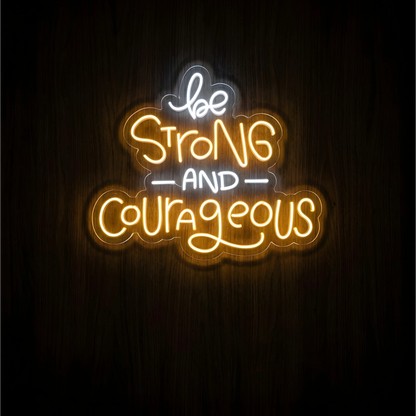 Be Strong and Courageous LED Neon Sign with warm yellow “Strong” and “Courageous” lettering and white “be” and “AND” on clear acrylic against a dark wood background, suited to bedrooms and home offices.