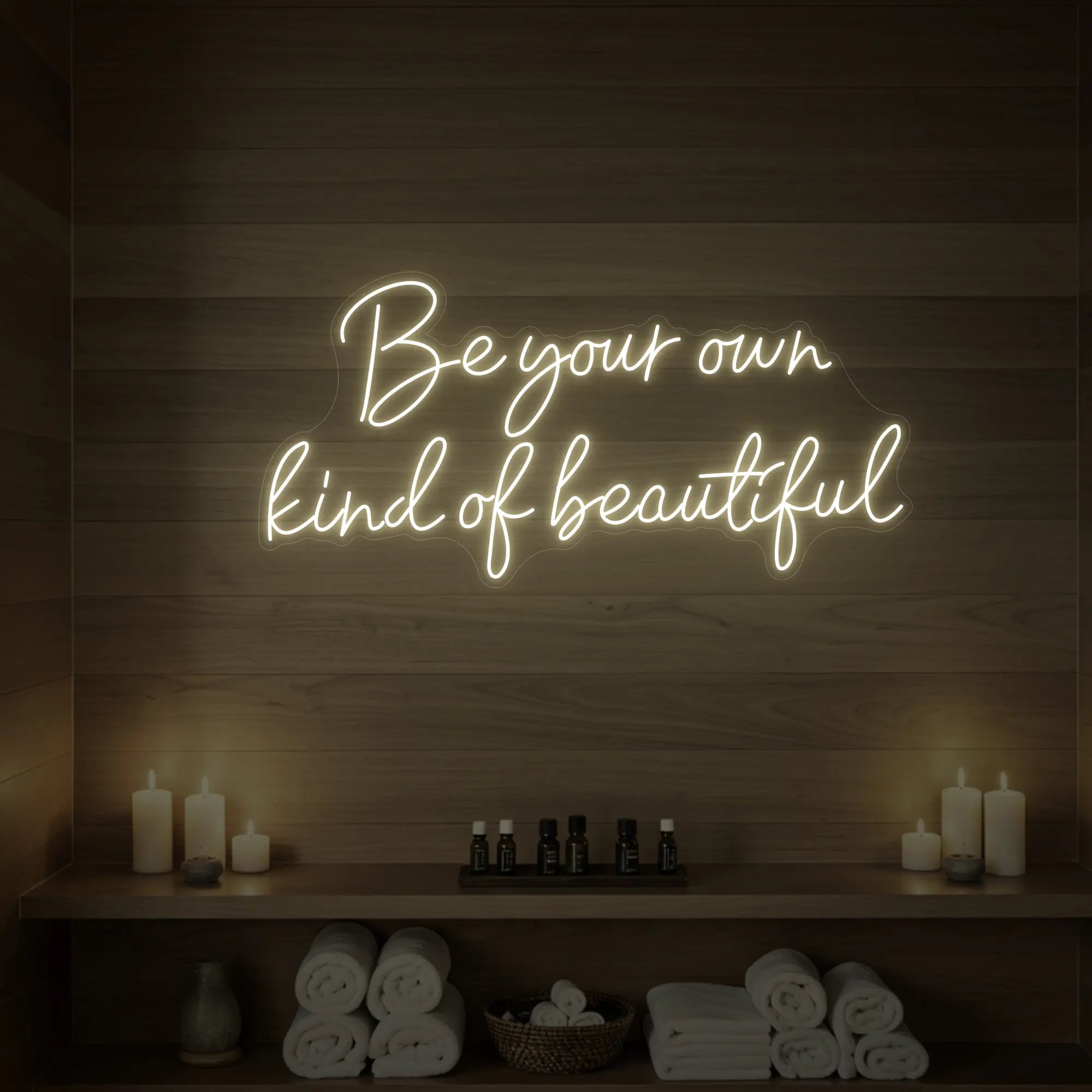 Photo of the 'Be Your Own Kind of Beautiful' neon sign glowing in warm white against a styled interior wall.