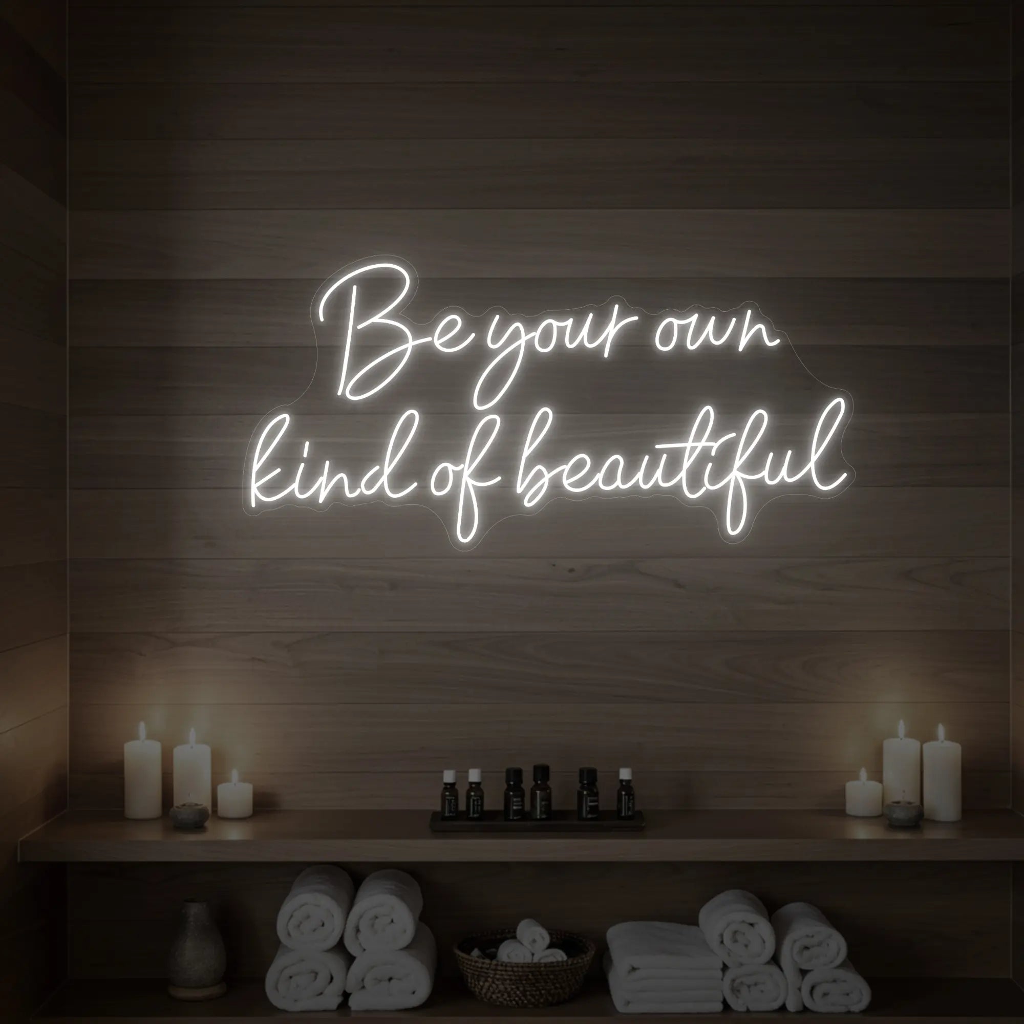 Photo of the 'Be Your Own Kind of Beautiful' neon sign glowing in cool white against a styled interior wall.