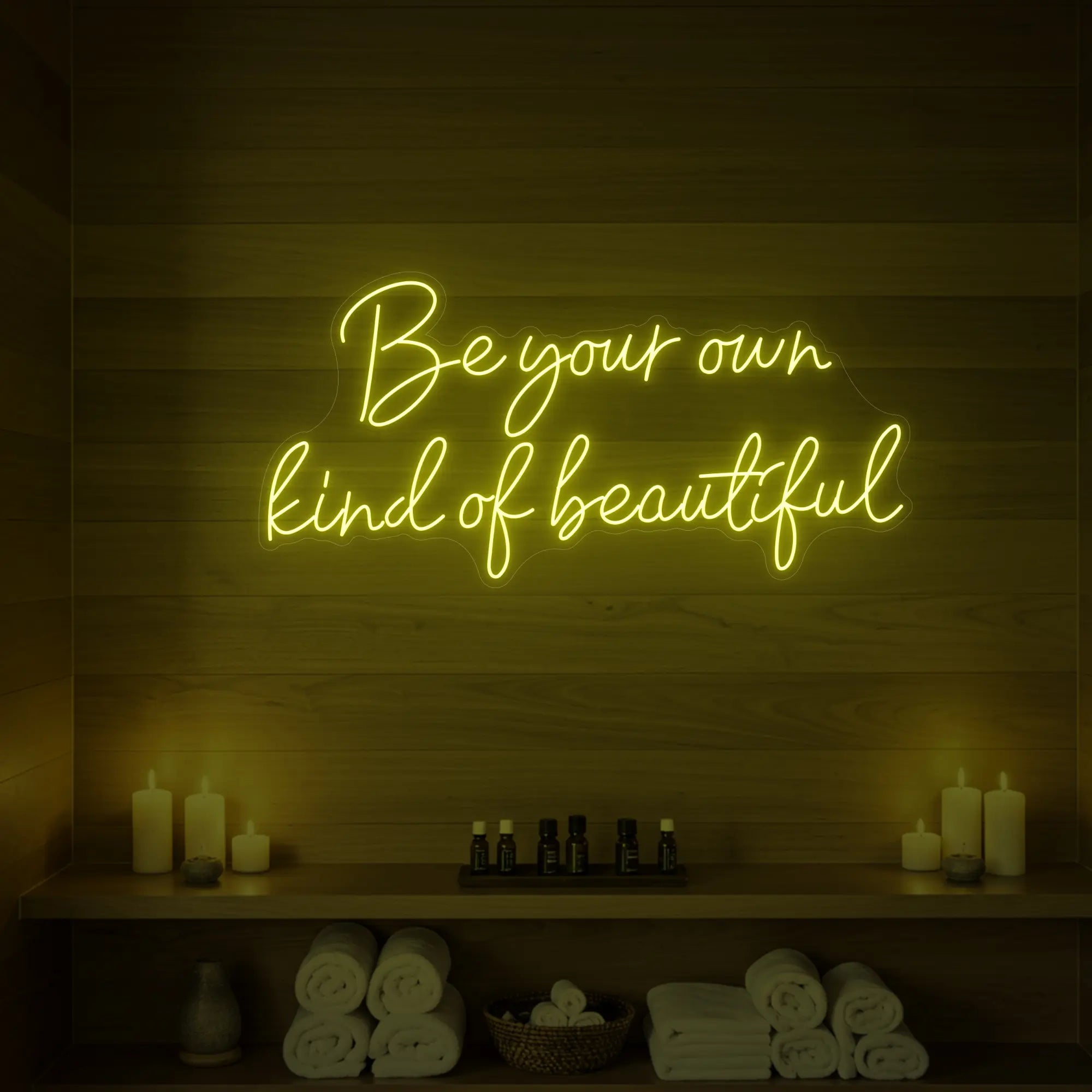Photo of the 'Be Your Own Kind of Beautiful' neon sign glowing in lemon yellow against a styled interior wall.
