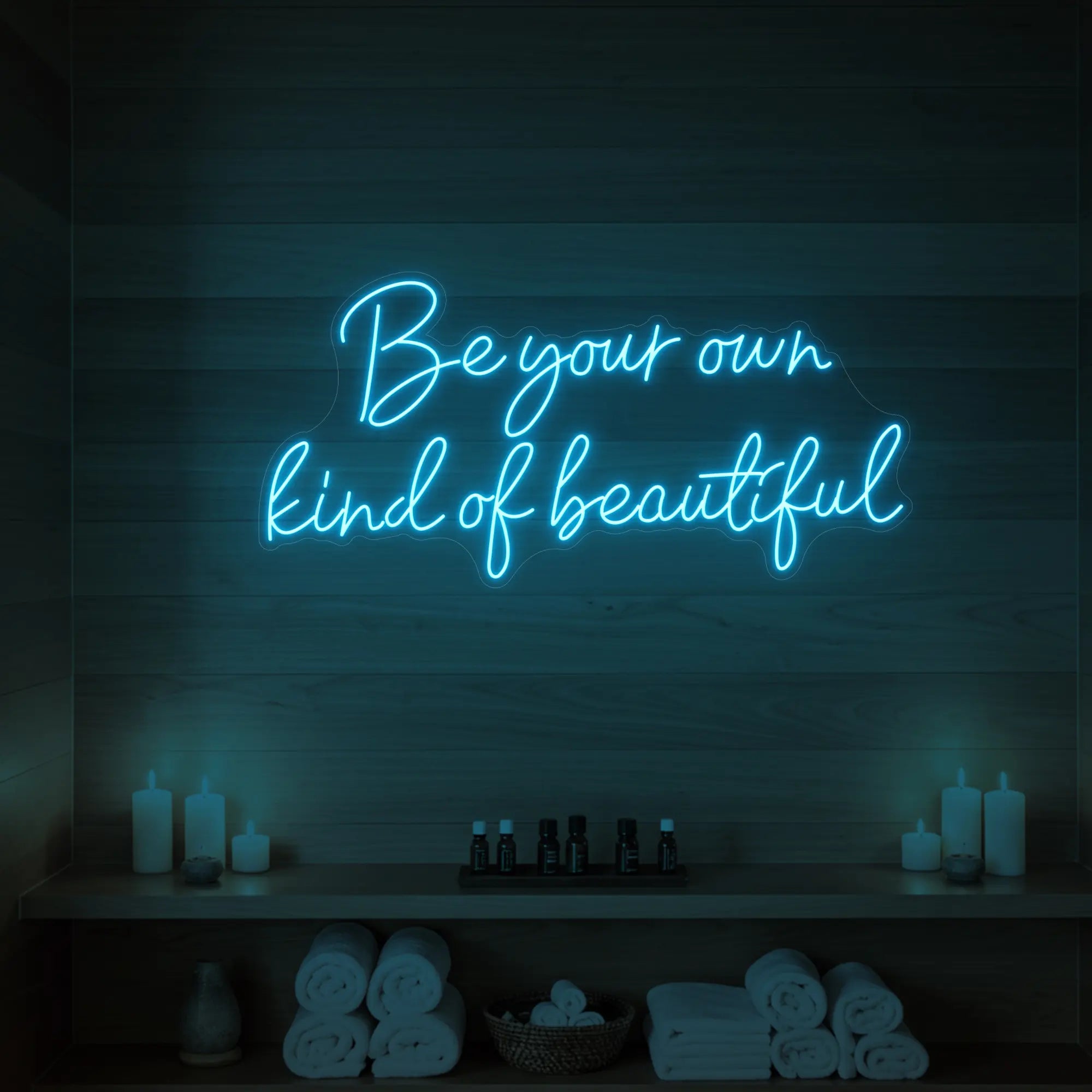 Photo of the 'Be Your Own Kind of Beautiful' neon sign glowing in ice blue against a styled interior wall.