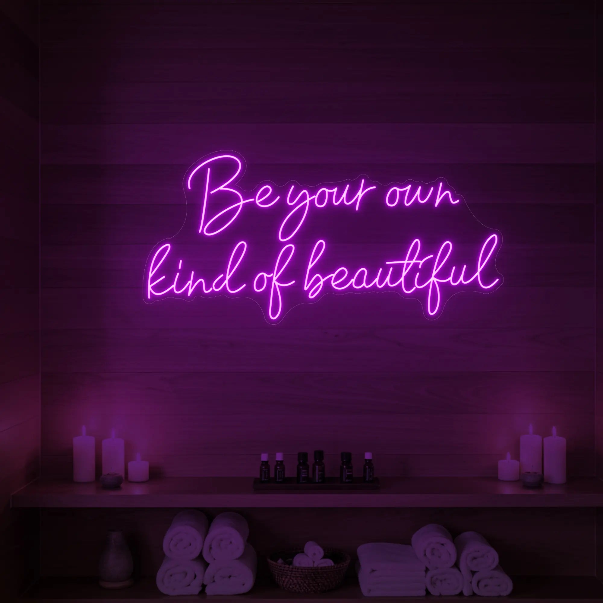 Photo of the 'Be Your Own Kind of Beautiful' neon sign glowing in deep pink against a styled interior wall.