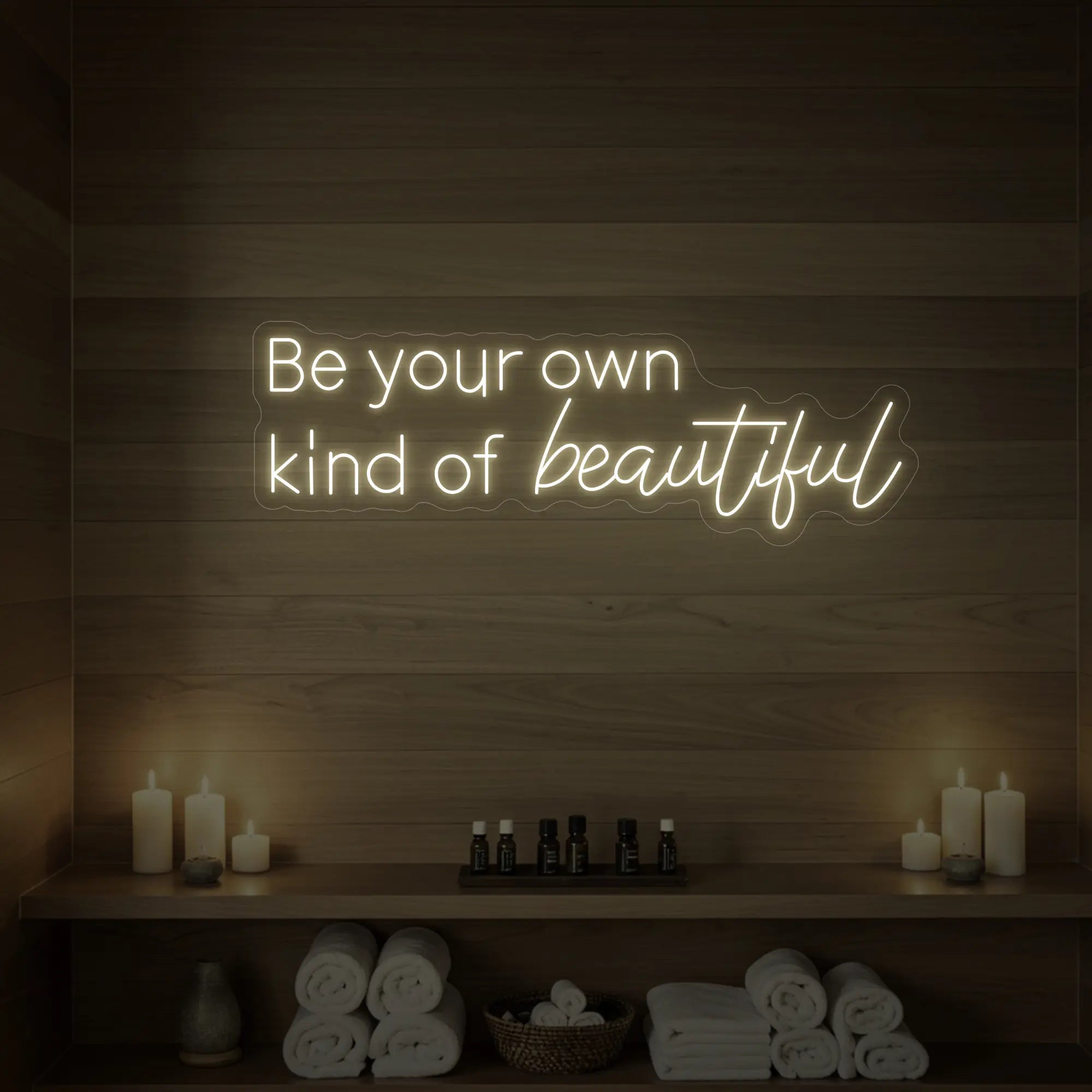 Photo of the 'Be your own kind of beautiful' neon sign glowing in warm white against a styled interior wall.