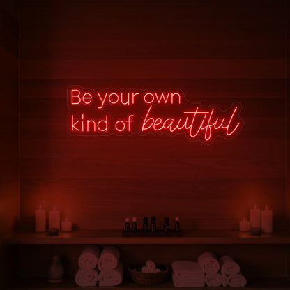 Photo of the 'Be your own kind of beautiful' neon sign glowing in red against a styled interior wall.