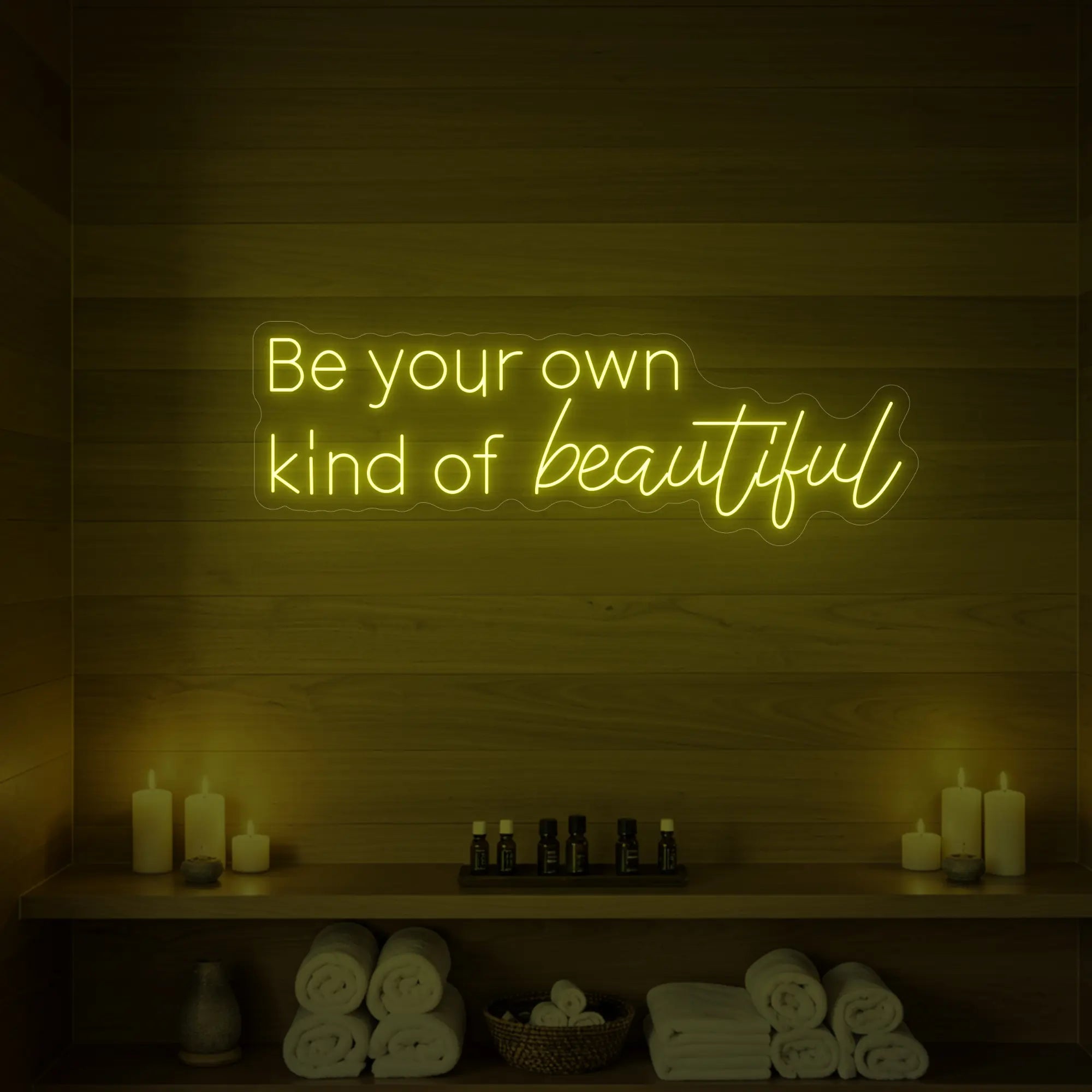 Photo of the 'Be your own kind of beautiful' neon sign glowing in lemon yellow against a styled interior wall.