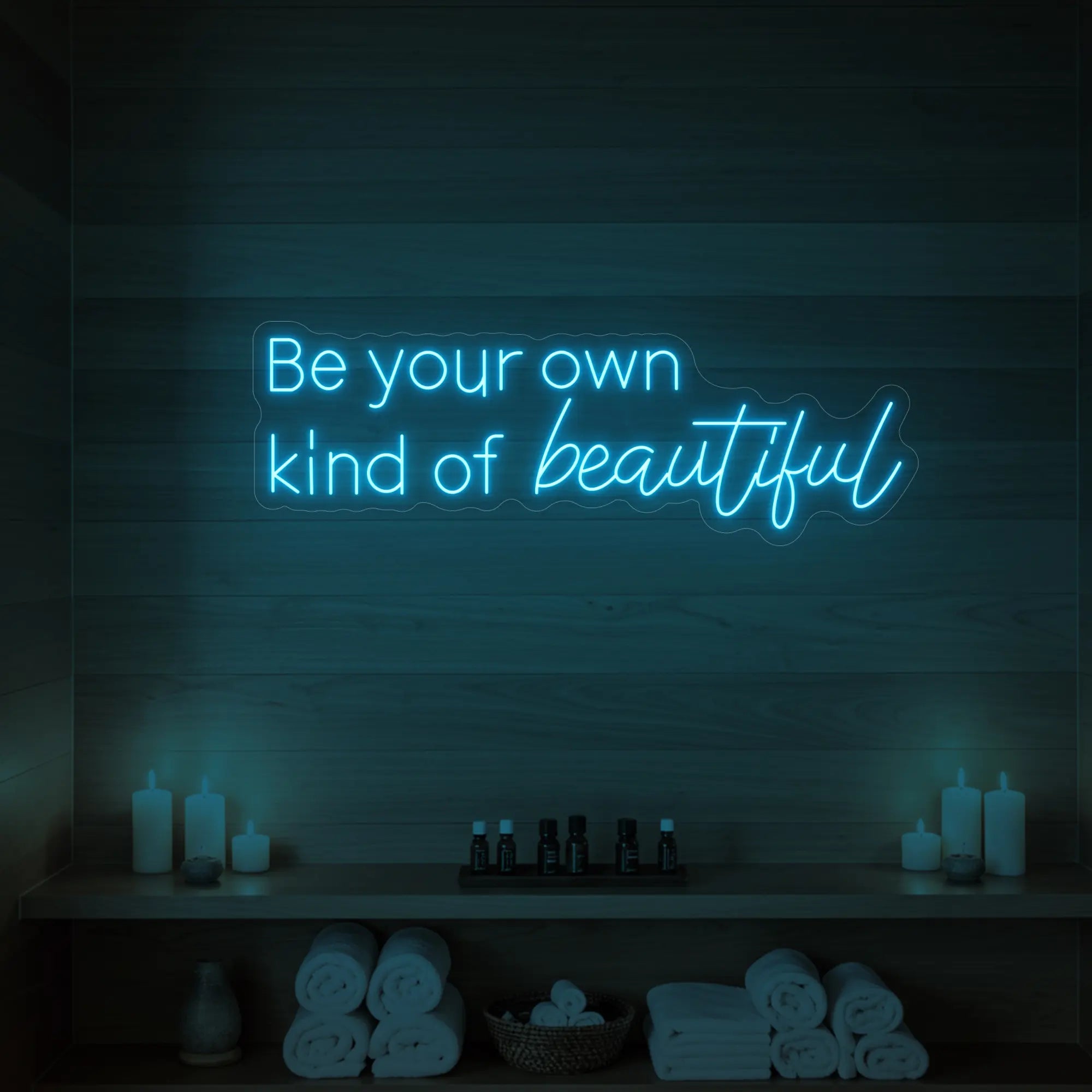 Photo of the 'Be your own kind of beautiful' neon sign glowing in ice blue against a styled interior wall.