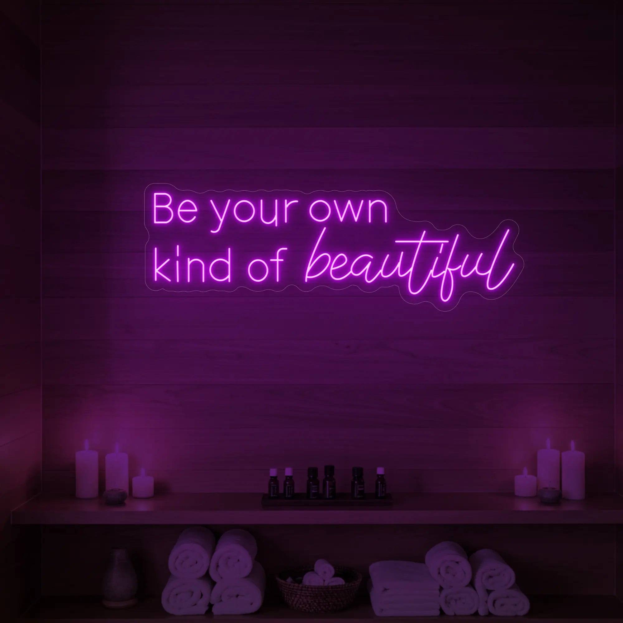 Photo of the 'Be your own kind of beautiful' neon sign glowing in deep pink against a styled interior wall.