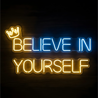“BELIEVE IN YOURSELF” LED Neon Sign with blue “BELIEVE,” yellow “YOURSELF,” and a small yellow crown above the first word, displayed on clear acrylic against a dark wood background, suited to bedrooms and study spaces.