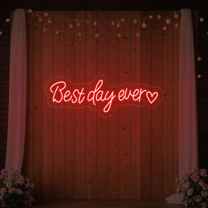 Photo of the 'Best Day Ever Heart' neon sign glowing in red against a styled interior wall.