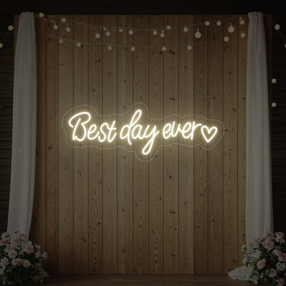 Photo of the 'Best Day Ever Heart' neon sign glowing in warm white against a styled interior wall.