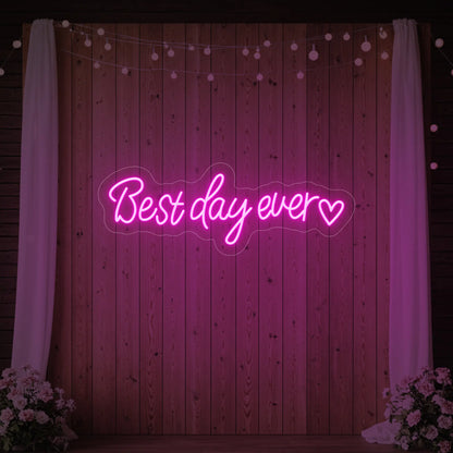 Photo of the 'Best Day Ever Heart' neon sign glowing in light pink against a styled interior wall.