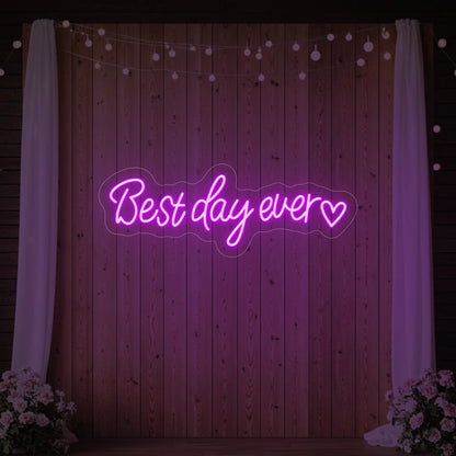 Photo of the 'Best Day Ever Heart' neon sign glowing in deep pink against a styled interior wall.
