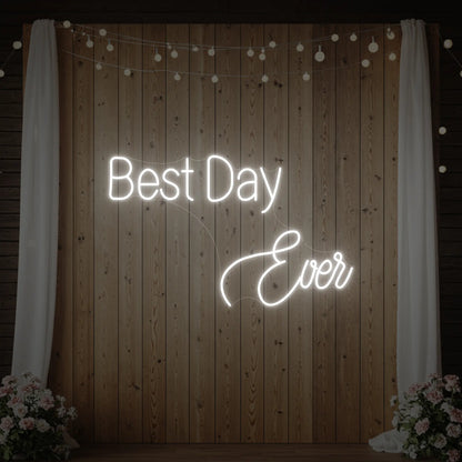 Photo of the 'Best Day Ever' neon sign glowing in cool white against a styled interior wall.