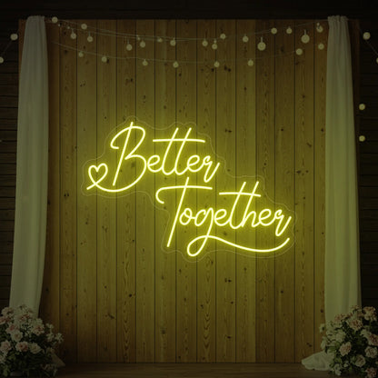 Photo of the 'Better Together' neon sign glowing in lemon yellow against a styled interior wall.