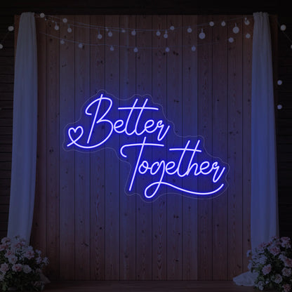 Photo of the 'Better Together' neon sign glowing in deep blue against a styled interior wall.