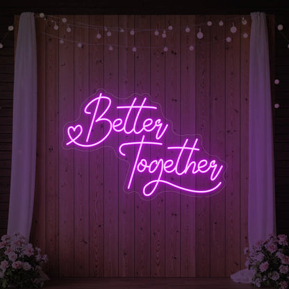 Photo of the 'Better Together' neon sign glowing in deep pink against a styled interior wall.
