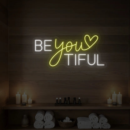 Photo of the 'BEYOUtiful' neon sign glowing in lemon yellow against a styled interior wall.
