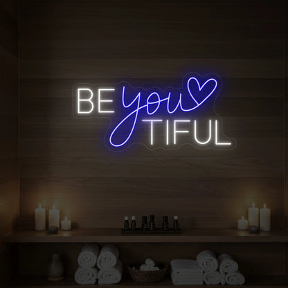 Photo of the 'BEYOUtiful' neon sign glowing in deep blue against a styled interior wall.