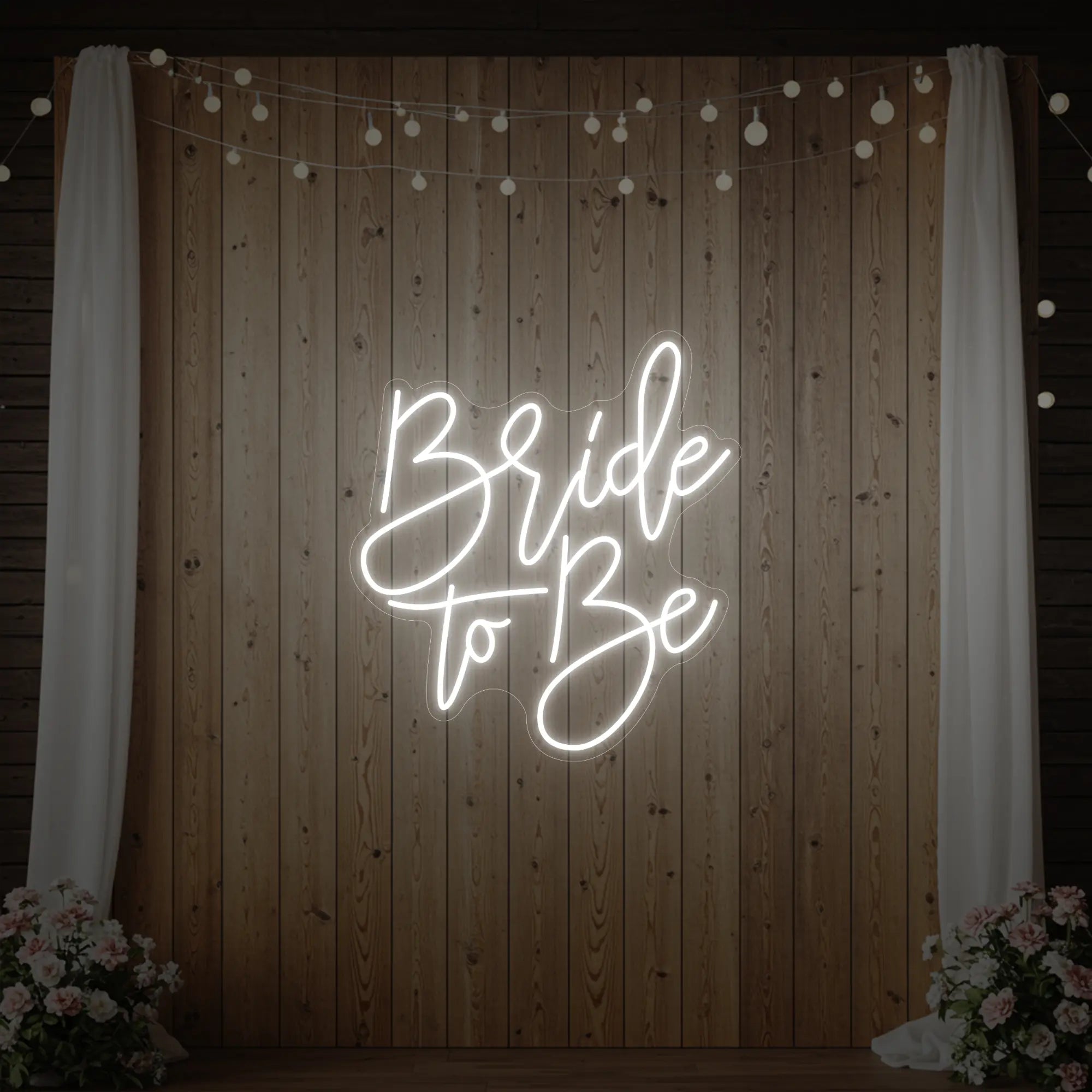 Photo of the 'Bride To Be' neon sign glowing in cool white against a styled interior wall.