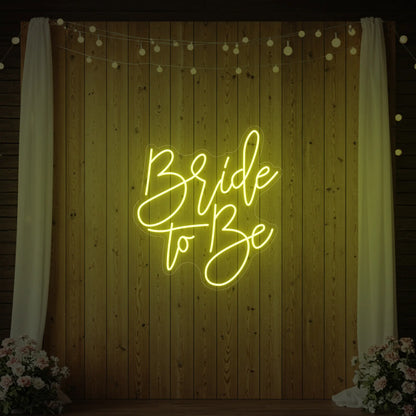 Photo of the 'Bride To Be' neon sign glowing in lemon yellow against a styled interior wall.