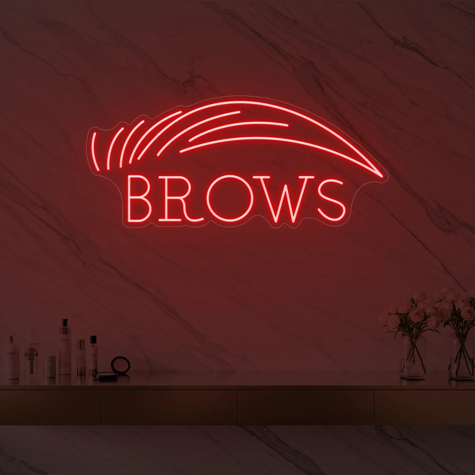 Photo of the 'BROWS' neon sign with an eyebrow graphic glowing in red against a styled interior wall.