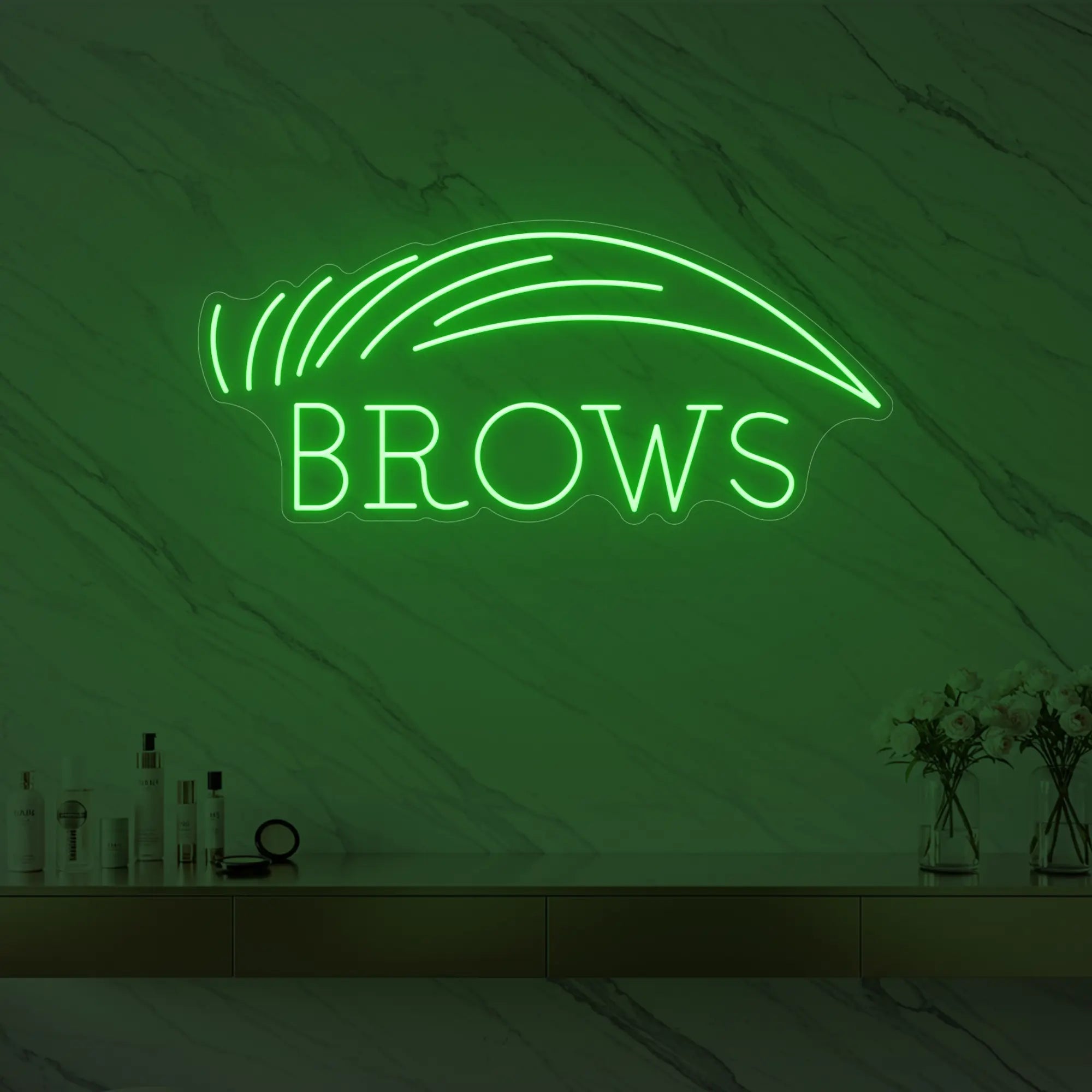 Photo of the 'BROWS' neon sign with an eyebrow graphic glowing in green against a styled interior wall.