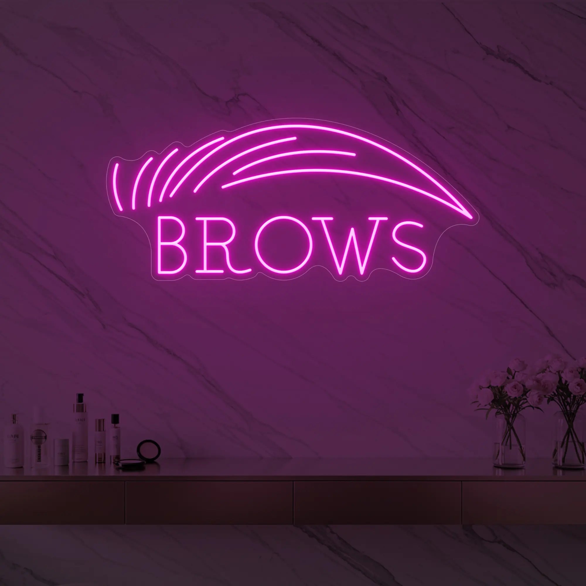 Photo of the 'BROWS' neon sign with an eyebrow graphic glowing in light pink against a styled interior wall.
