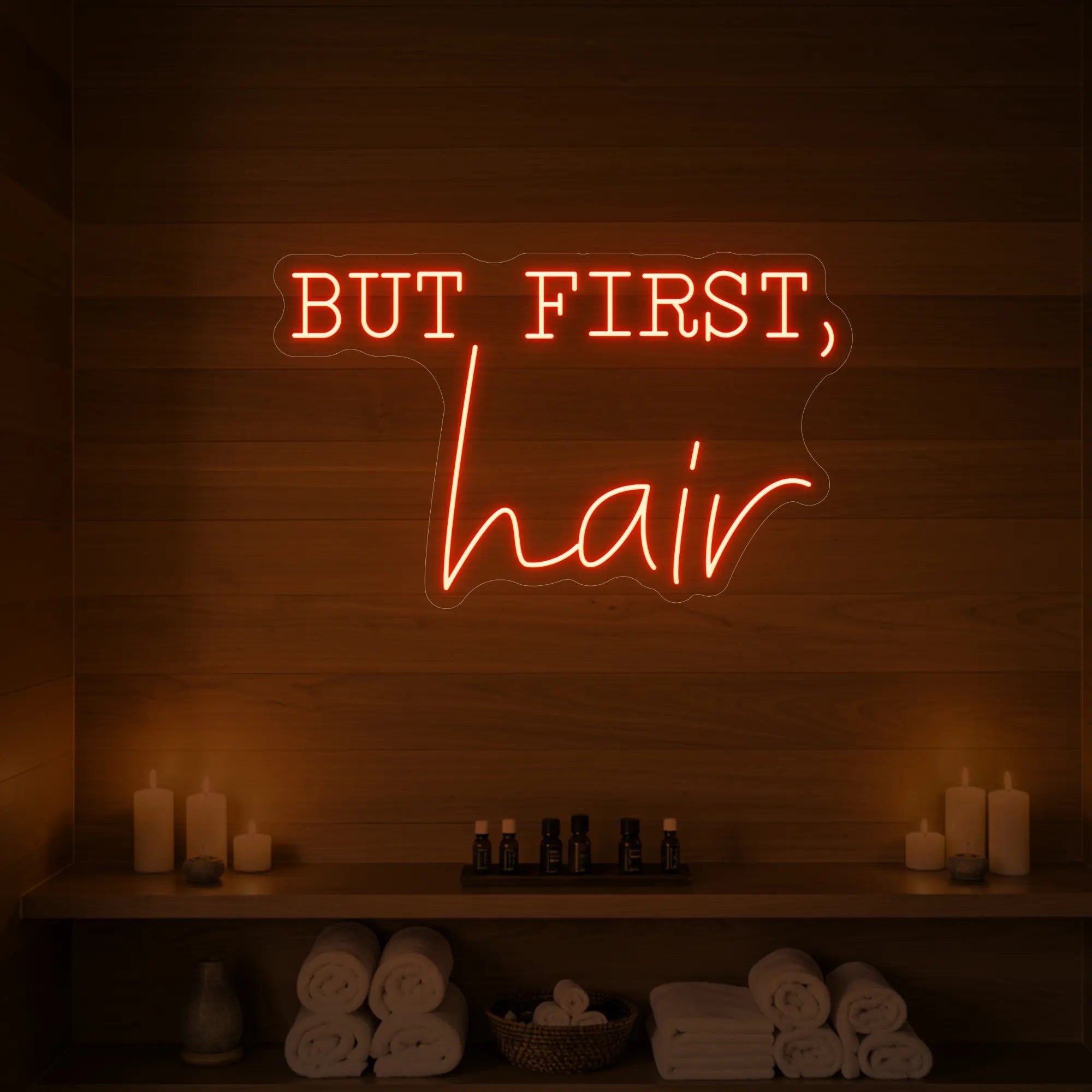 Photo of the 'BUT FIRST, hair' neon sign glowing in golden yellow against a styled interior wall.