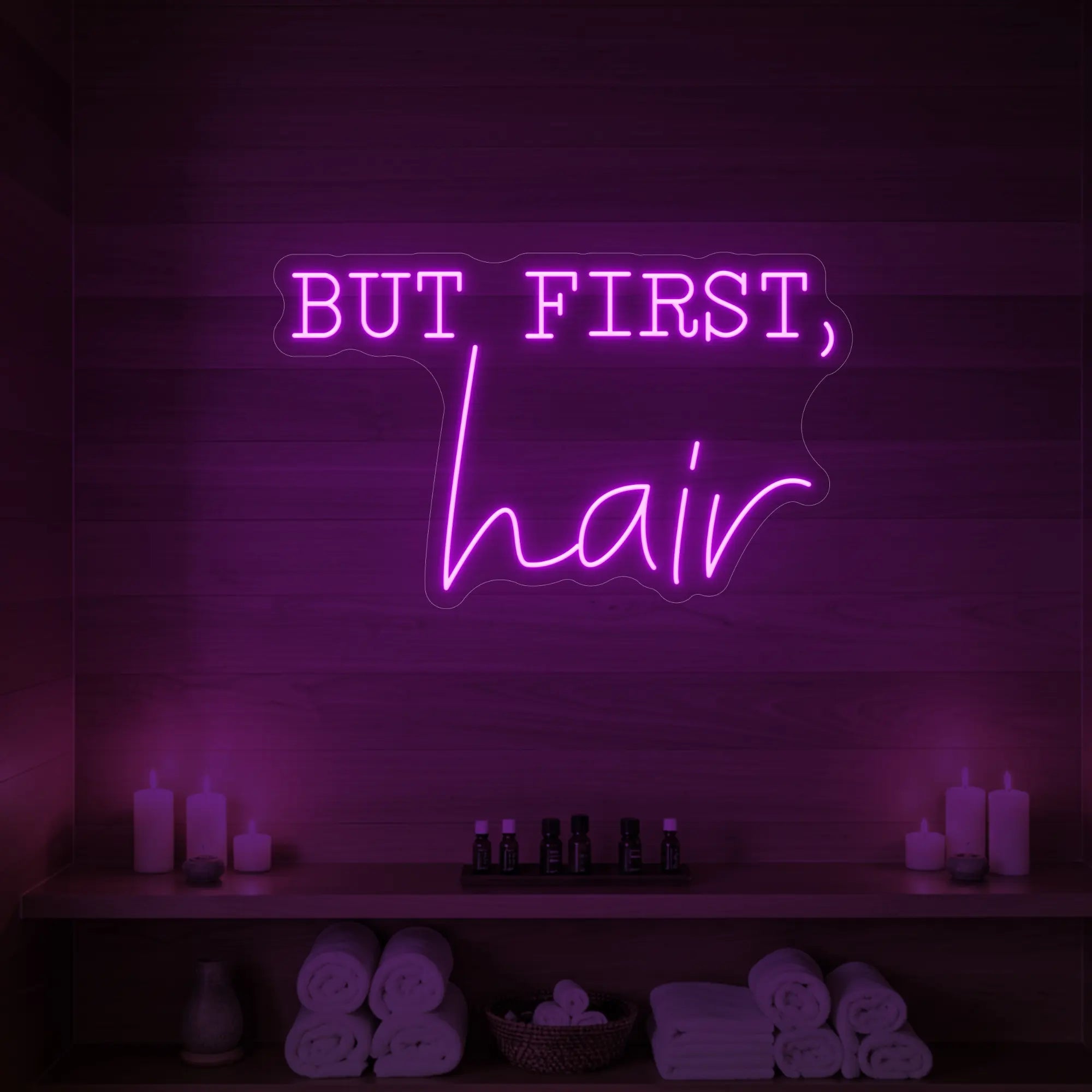 Photo of the 'BUT FIRST, hair' neon sign glowing in deep pink against a styled interior wall.