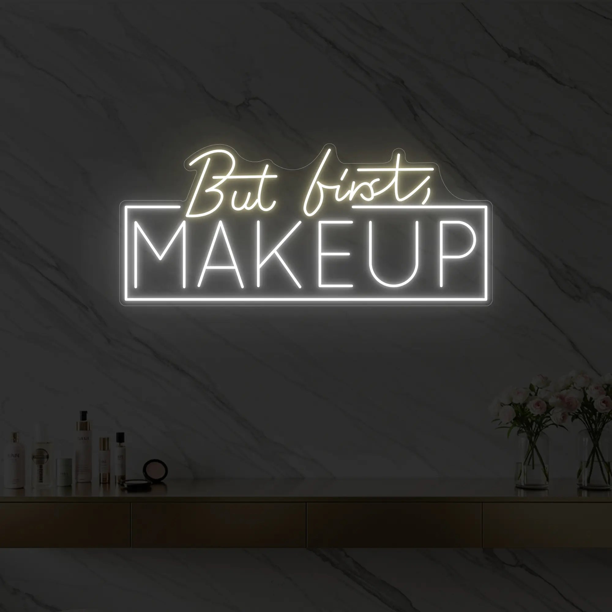 Photo of the 'But first, MAKEUP' neon sign glowing in warm white against a styled interior wall.