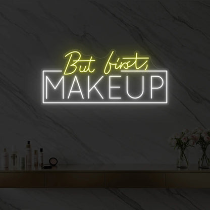 Photo of the 'But first, MAKEUP' neon sign glowing in lemon yellow against a styled interior wall.