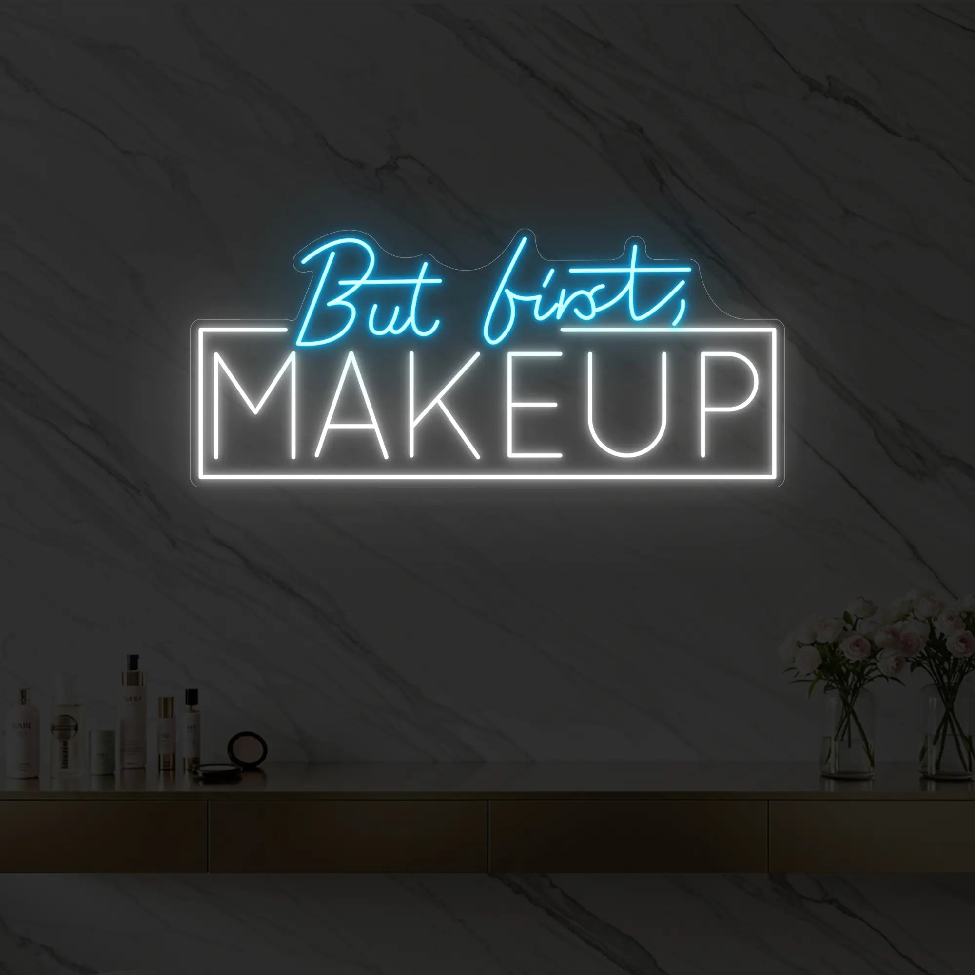 Photo of the 'But first, MAKEUP' neon sign glowing in ice blue against a styled interior wall.