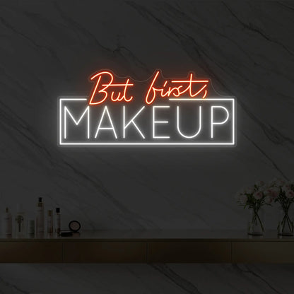 Photo of the 'But first, MAKEUP' neon sign glowing in golden yellow against a styled interior wall.