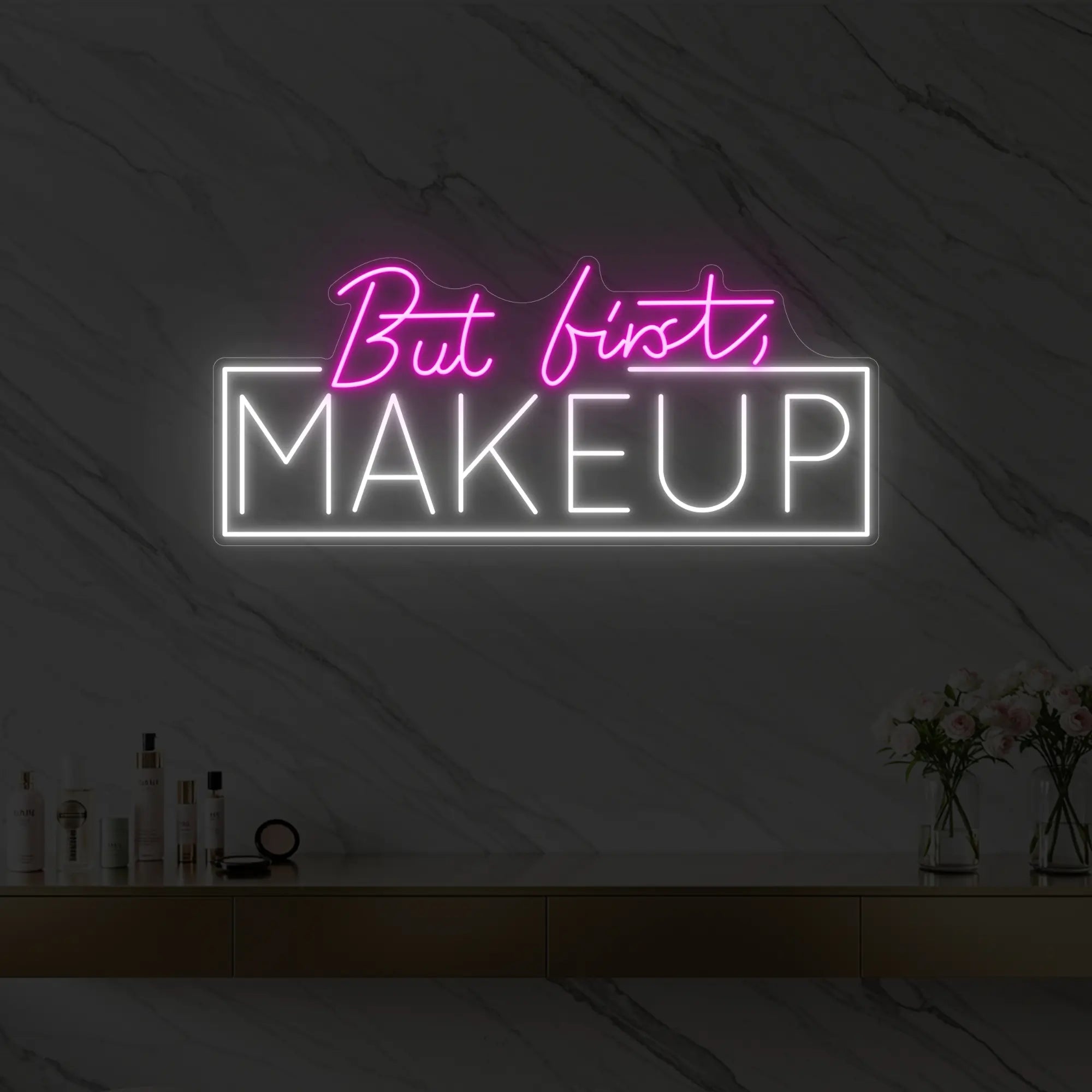 Photo of the 'But first, MAKEUP' neon sign glowing in light pink against a styled interior wall.