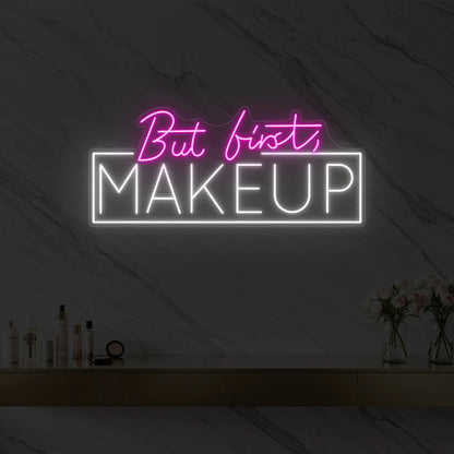Photo of the 'But first, MAKEUP' neon sign glowing in light pink against a styled interior wall.
