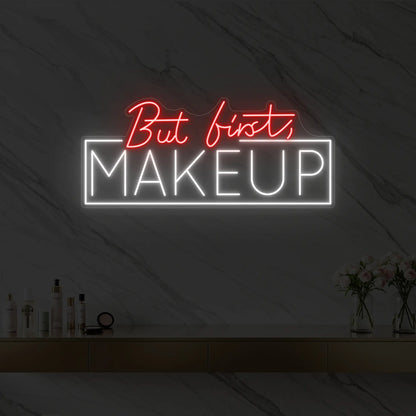 Photo of the 'But first, MAKEUP' neon sign glowing in red against a styled interior wall.