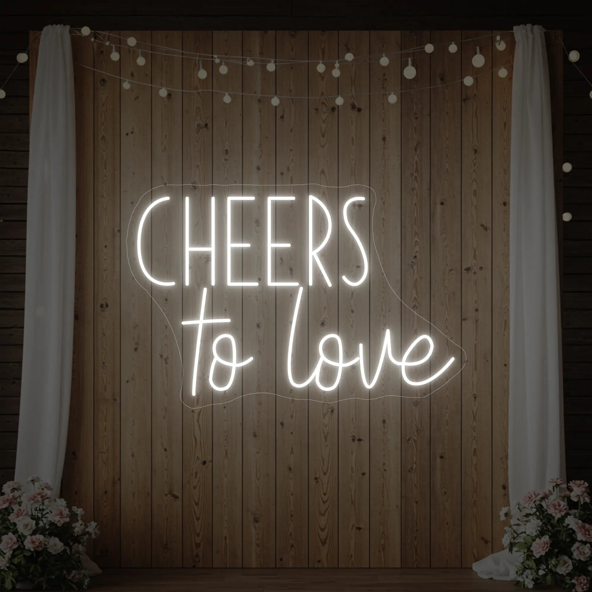 Photo of the 'Cheers To Love' neon sign glowing in cool white against a styled interior wall.