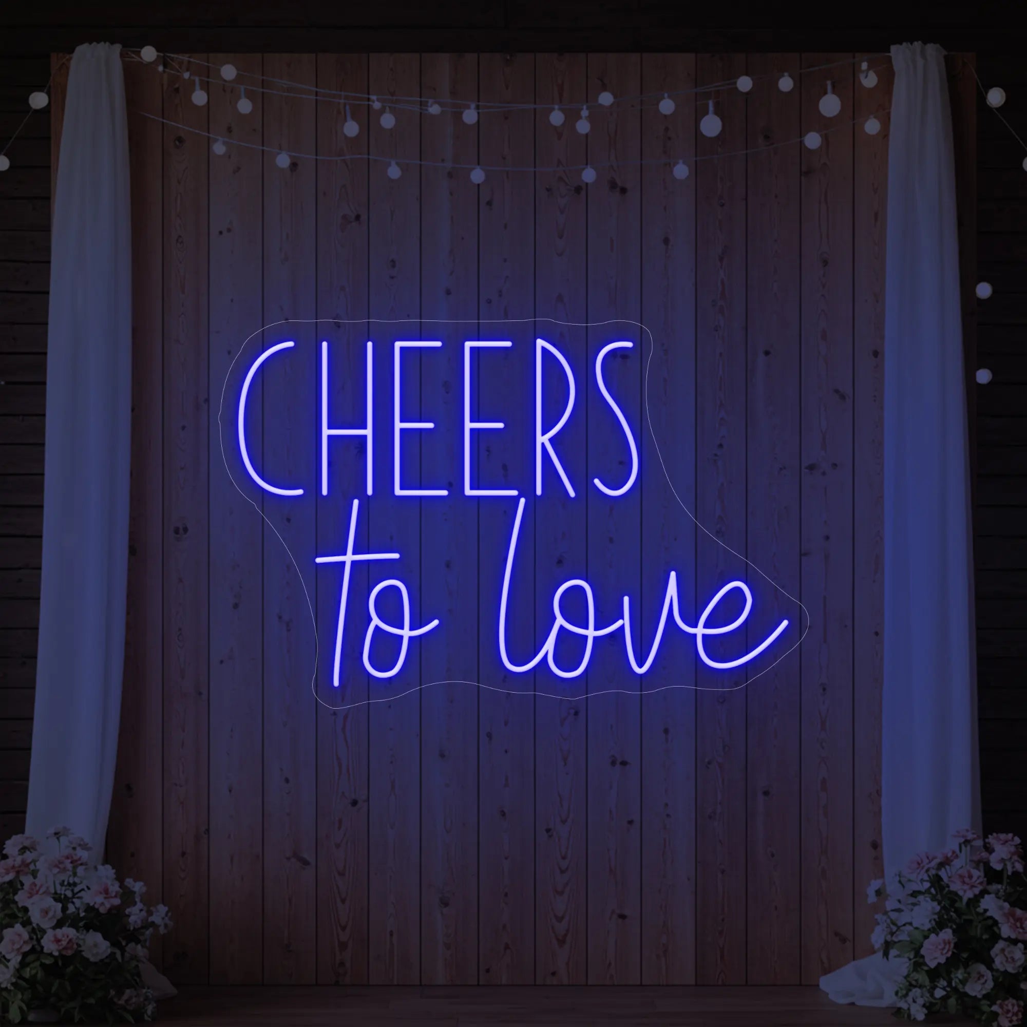 Photo of the 'Cheers To Love' neon sign glowing in deep blue against a styled interior wall.