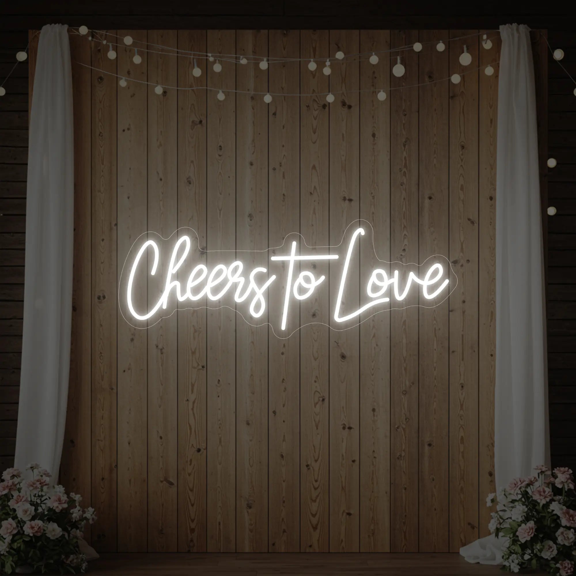 Photo of the 'Cheers To Love' neon sign glowing in cool white against a styled interior wall.