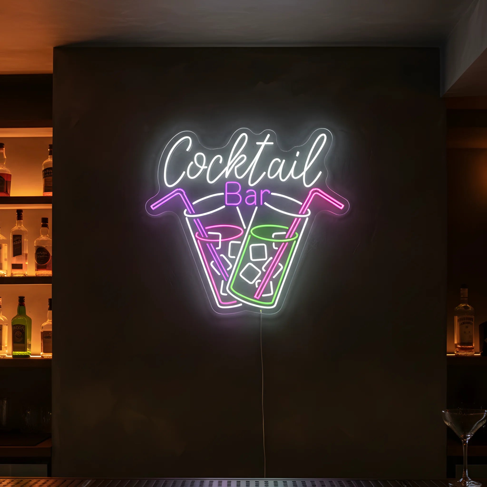 Photo of the 'COCKTAIL BAR' neon sign glowing in multi-color against a styled interior wall.