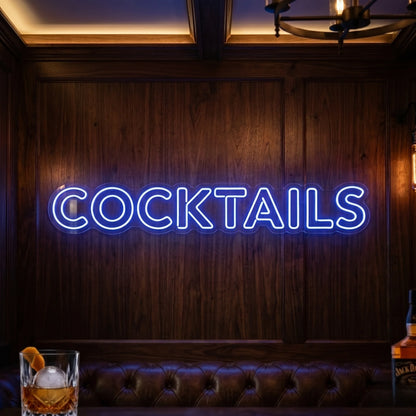 Photo of the 'COCKTAILS' neon sign glowing in deep blue against a styled interior wall.