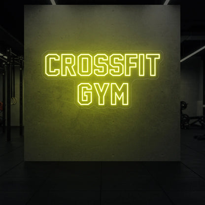  'CrossFit Gym' neon sign glowing in lemon yellow against a styled interior wall.