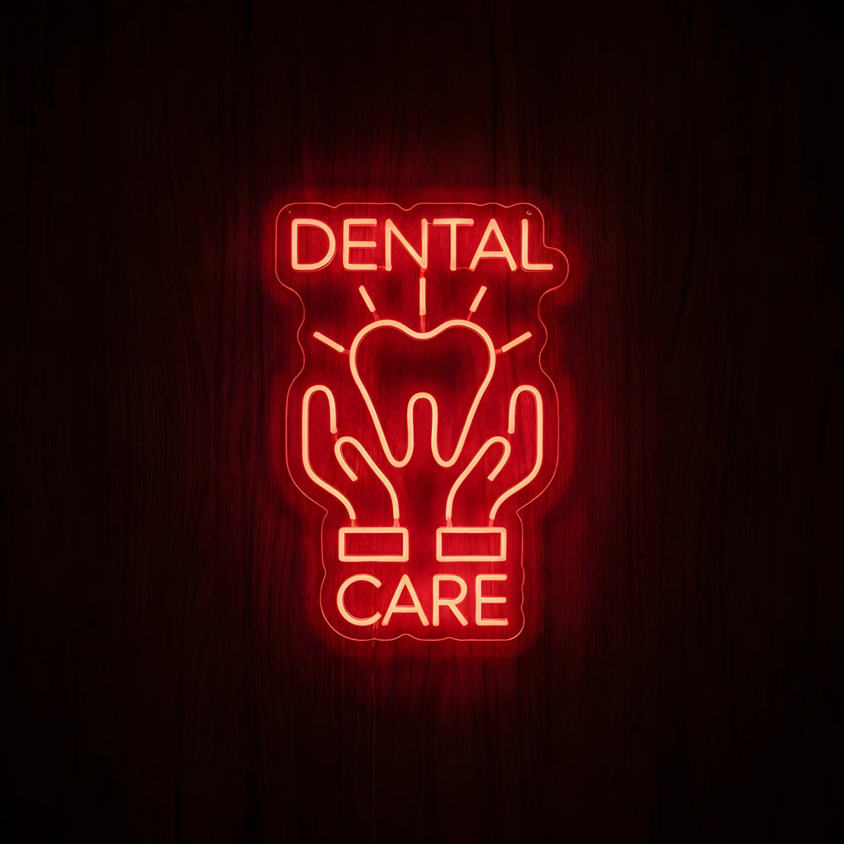Dental Care Hands LED neon sign featuring a glowing red tooth supported by two hands, radiant accents, and Dental Care lettering on clear acrylic backing against a dark wooden wall.