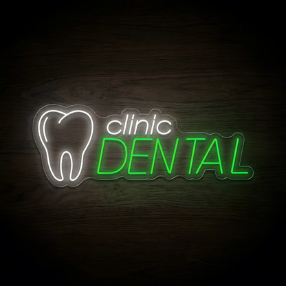 Dental Clinic Logo LED neon sign featuring a glowing white tooth outline, white clinic lettering, and vibrant green DENTAL text on clear acrylic backing, displayed against a dark wooden wall.