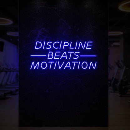  'Discipline Beats Motivation' neon sign glowing in deep blue against a styled interior wall.