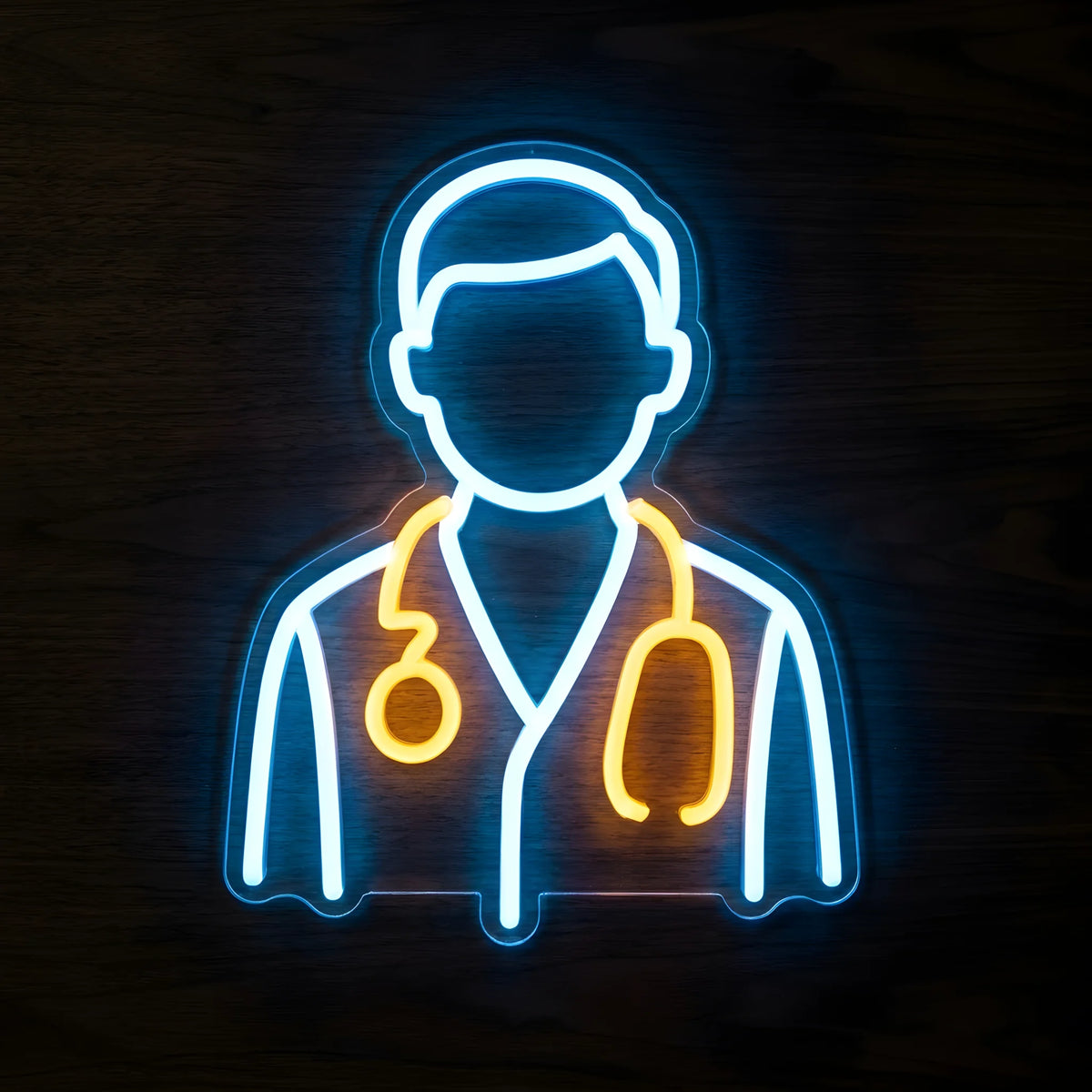 Doctor Medical Uniform LED Neon Sign featuring a minimalist doctor silhouette outlined in blue and white neon with a glowing yellow stethoscope on clear cut-to-shape acrylic against a dark wooden wall.
