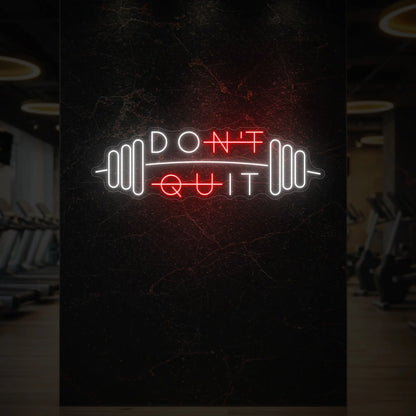 'Don’t Quit (with Barbell)' neon sign glowing in red against a styled interior wall.