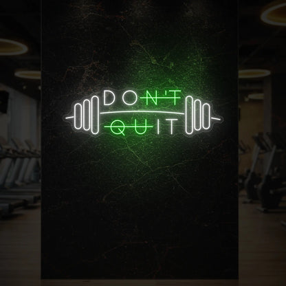  'Don’t Quit (with Barbell)' neon sign glowing in green against a styled interior wall.