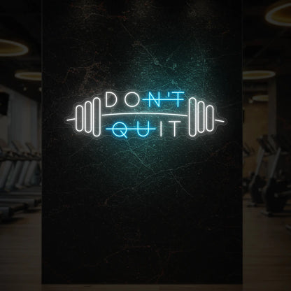  'Don’t Quit (with Barbell)' neon sign glowing in ice blue against a styled interior wall.